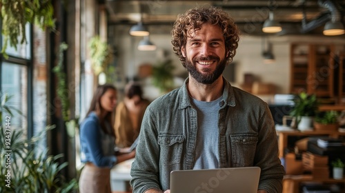 Professional man standing confidently with laptop in a modern office space