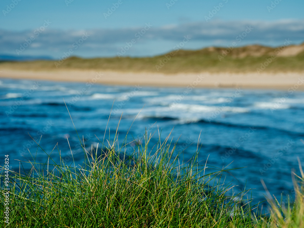 Green grass grows on cliff and amazing waves and sandy Bundoran beach in Ireland on warm sunny day. Popular tourist and surfers area. Blue cloudy sky. Irish landscape. Rich saturated color. Green grass grows on cliff and amazing waves and sandy Bundoran beach in Ireland on warm sunny day. Popular tourist and surfers area. Blue cloudy sky. Irish landscape. Rich saturated color.