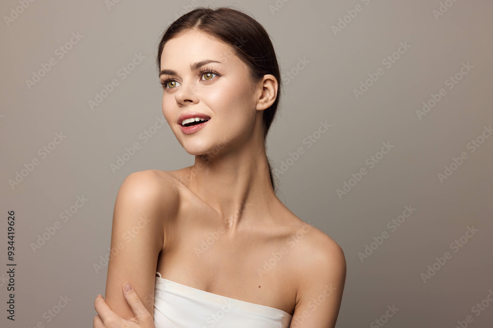 Beautiful young woman posing with hands on hips, looking at the camera on a gray background Beautiful young woman posing with hands on hips, looking at the camera on a gray background