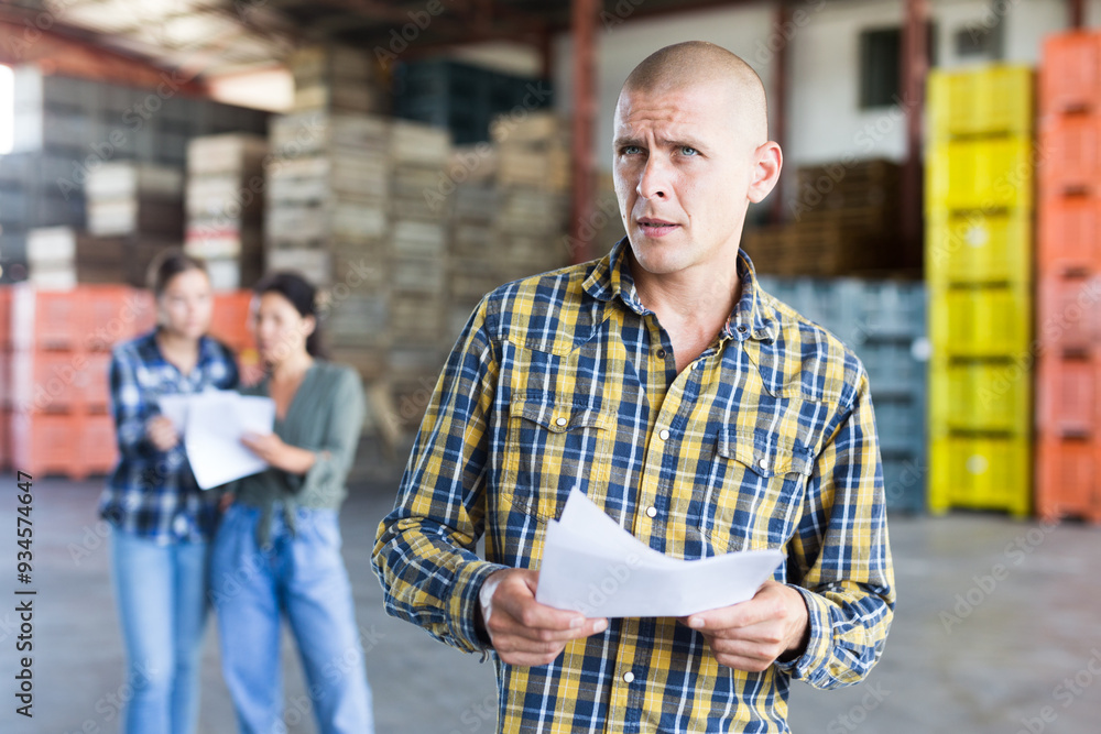 Obraz premium Confident male manager with documents inside a large warehouse