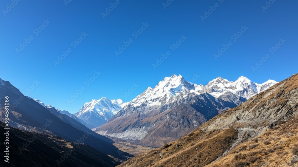 Fototapeta premium Majestic mountain range with snow-capped peaks and clear blue sky above. Majestic Mountain Range