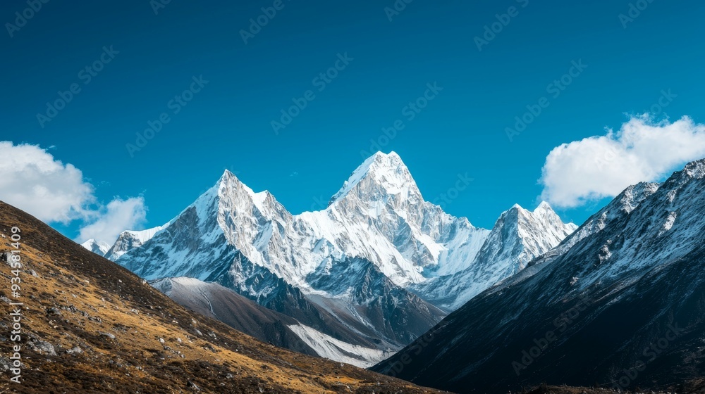 Obraz premium Majestic mountain range with snow-capped peaks and clear blue sky above. Majestic Mountain Range