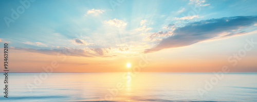 The sun is setting over the ocean, casting a warm glow on the water. The sky is filled with clouds, creating a serene and peaceful atmosphere