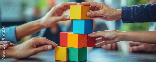 Hands of diverse people stacking blocks to build a tower, representing teamwork and cooperation