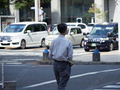 朝の都市のオフィス街で通勤する男性サラリーマンの姿