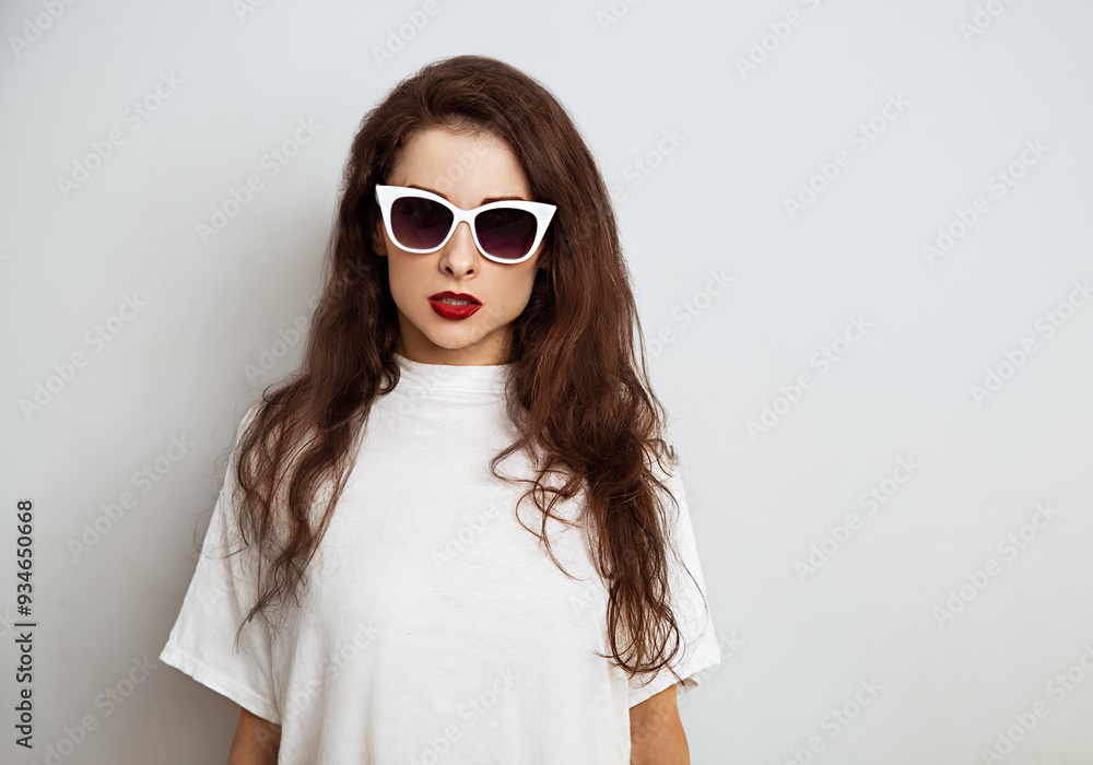 Beautiful brunette woman with red lipstick posing in fashion white sunglasses in white t-shirt on studio empty copy space background. Closeup Beautiful brunette woman with red lipstick posing in fashion white sunglasses in white t-shirt on studio empty copy space background. Closeup