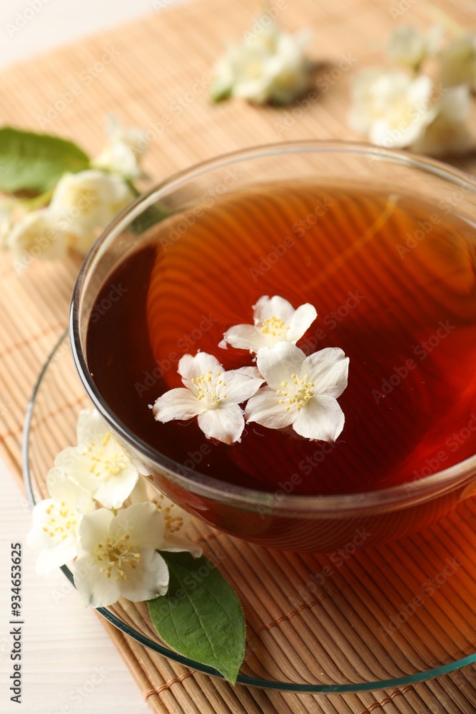 Hot jasmine tea in cup and flowers on white wooden table, closeup Hot jasmine tea in cup and flowers on white wooden table, closeup