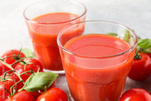 Tasty tomato juice in glasses, basil and fresh vegetables on table, closeup