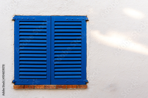 Blue window with shutters with brick windowsill with space on a white wall