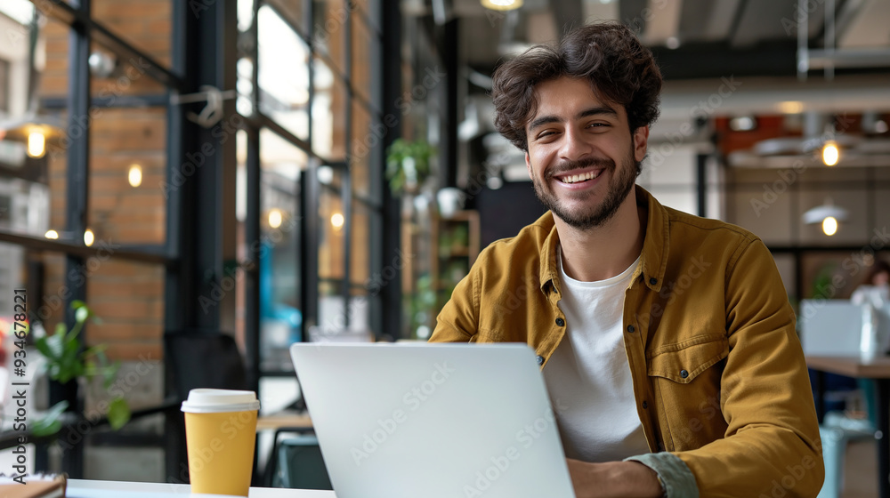 Portrait of smiling young male businessman working on laptop sitting in modern office drinking coffee in recyclable cup, happy businessman Portrait of smiling young male businessman working on laptop sitting in modern office drinking coffee in recyclable cup, happy businessman