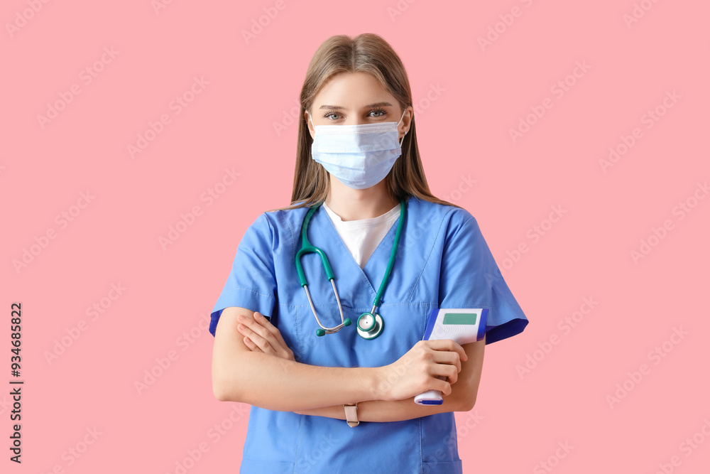 Female doctor in medical mask with infrared thermometer on pink background Female doctor in medical mask with infrared thermometer on pink background