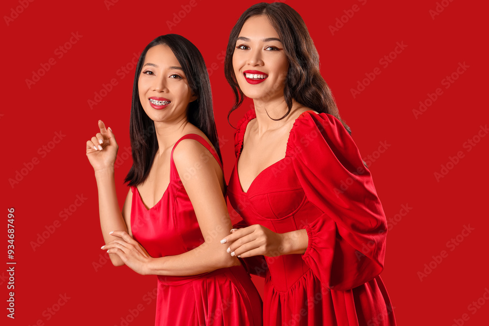 Beautiful young happy Asian women in stylish elegant outfits on red background Beautiful young happy Asian women in stylish elegant outfits on red background