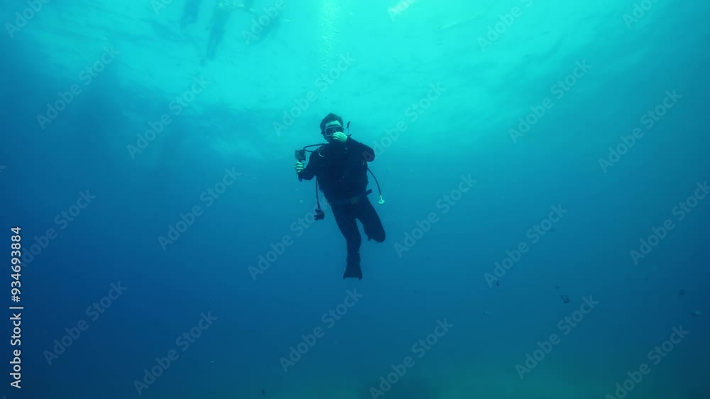 Underwater enthusiast rises smoothly to surface of deep ocean Underwater enthusiast rises smoothly to surface of deep ocean