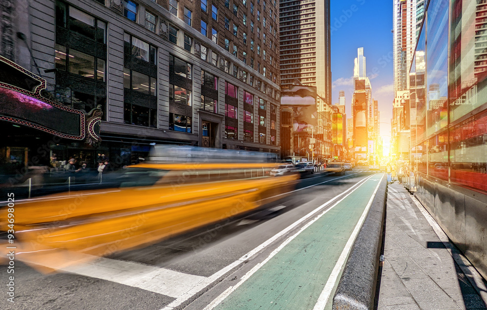 Yellow taxi with motion blur effect driving through Times Square in New York City on a sunny summer day