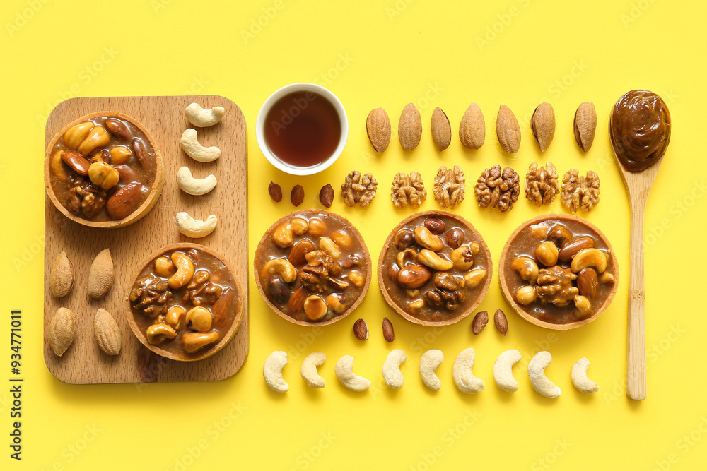 Tasty tarts with many different nuts and caramel on yellow background Tasty tarts with many different nuts and caramel on yellow background