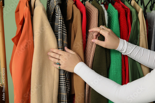 Woman and rack with hanging autumn clothes. Closeup