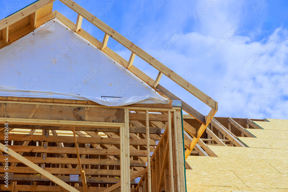 Obraz premium Installation of plywood on wooden roofing trusses at house under construction after roof has been assembled