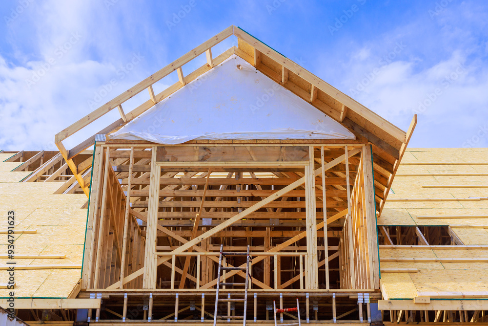 Installation of plywood on wooden roof trusses for house that is being constructed Installation of plywood on wooden roof trusses for house that is being constructed
