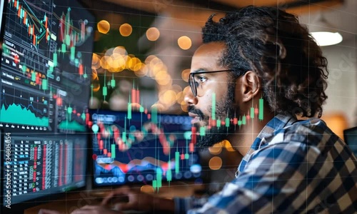 Wallpaper Mural Focused on the Market: A man intently analyzes financial data on multiple screens, the green lines of stock charts overlaying his focused gaze.  He embodies the dedication and precision required for s Torontodigital.ca
