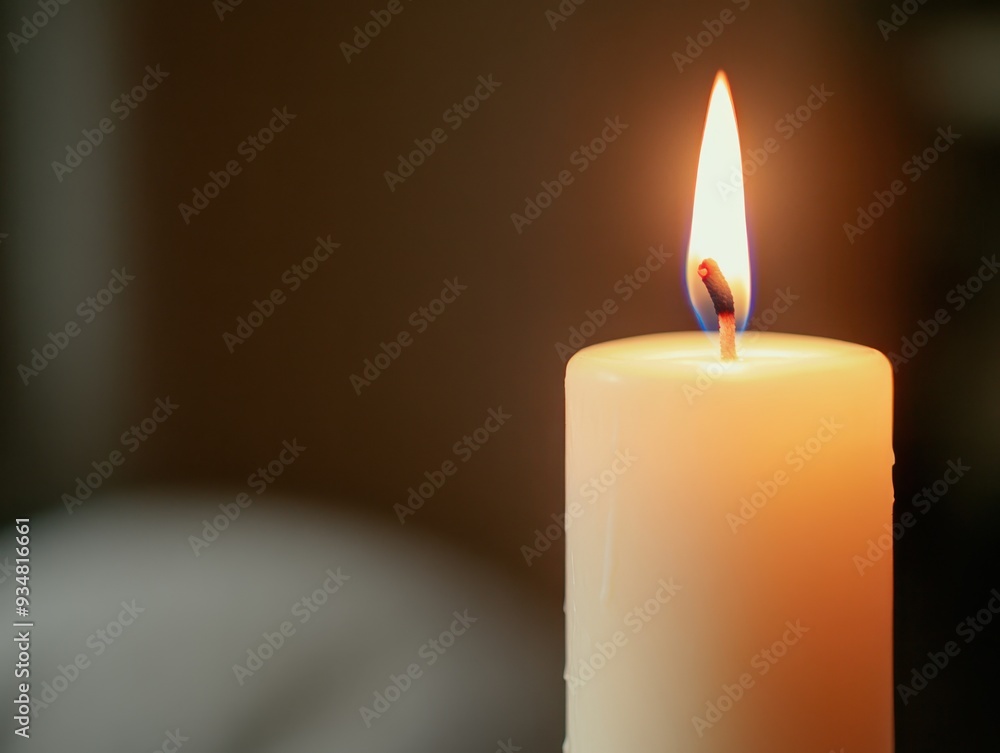 A serene candle flickers gently, casting a warm glow in a dim environment, perfect for creating a peaceful atmosphere.