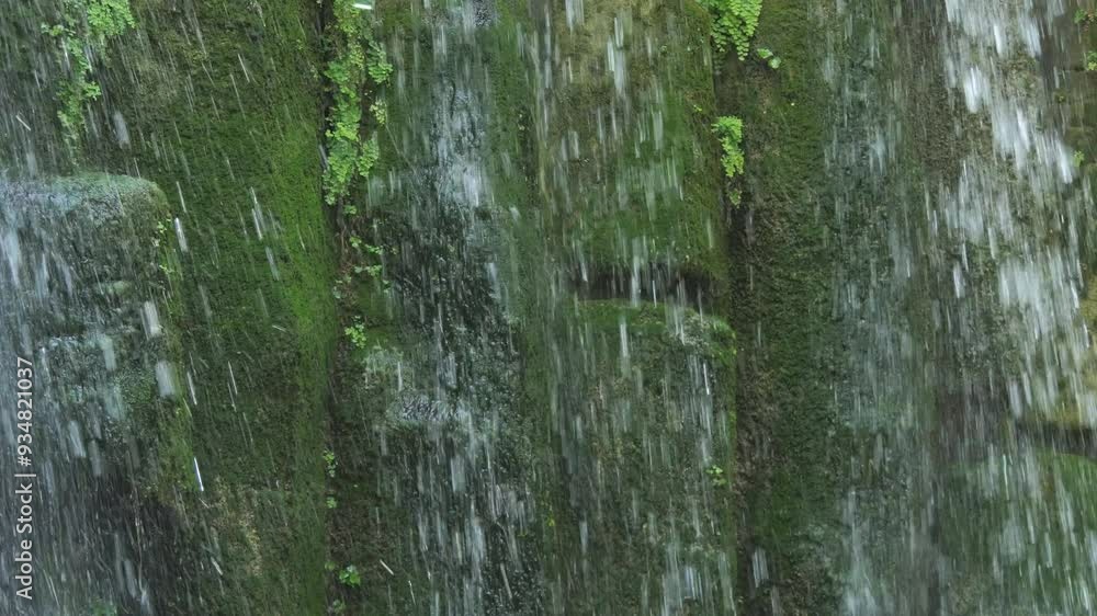 Tropical waterfall on the background of stones and various green plants. Falling water in slow motion Tropical waterfall on the background of stones and various green plants. Falling water in slow motion