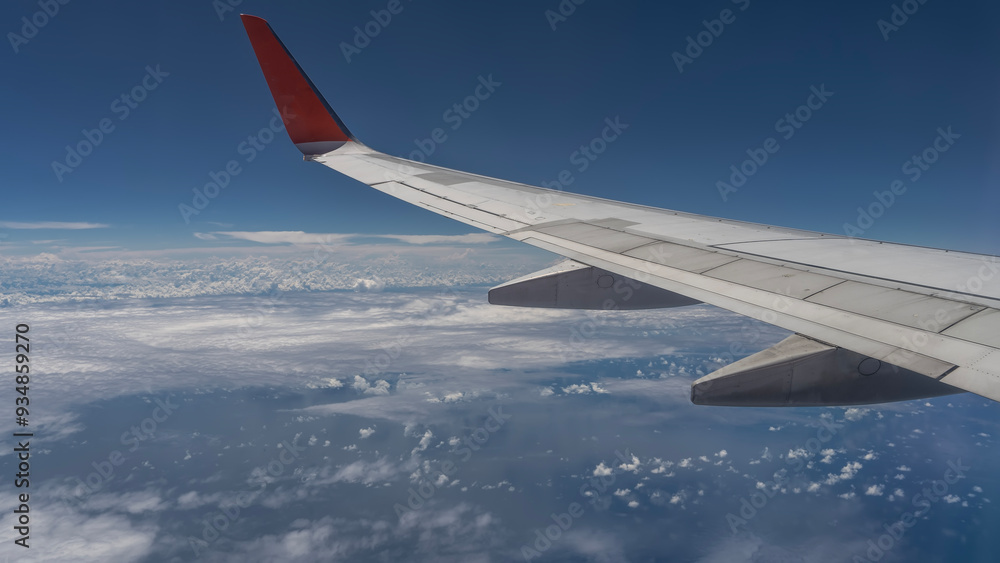 An airplane wing on a blue sky background. Close-up. Below is the ocean, white clouds. Malaysia. An airplane wing on a blue sky background. Close-up. Below is the ocean, white clouds. Malaysia.