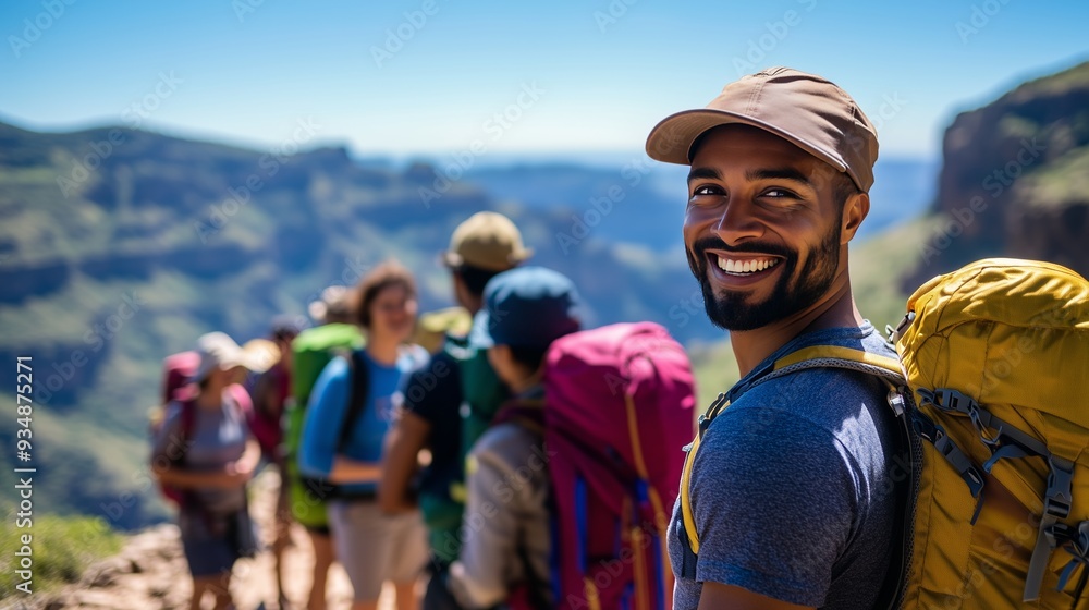 A joyful man with friends in colorful backpacks enjoys a sunny hike with stunning views.
