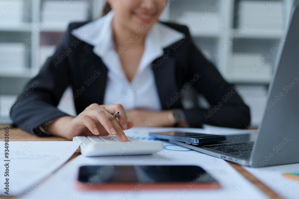 woman meticulously plans a finance audit, using a computer and calculator to review budget documents and ensure accuracy woman meticulously plans a finance audit, using a computer and calculator to review budget documents and ensure accuracy