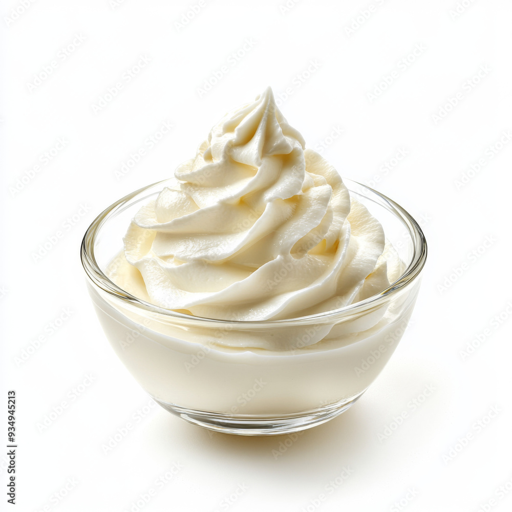 A bowl of whipped cream is sitting on a white background. The whipped cream is in a glass bowl and has a lot of air bubbles in it A bowl of whipped cream is sitting on a white background. The whipped cream is in a glass bowl and has a lot of air bubbles in it