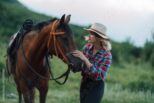 Happy blonde with horse in forest. Woman and a horse walking through the field during the day. Dressed in a plaid shirt and black leggings.