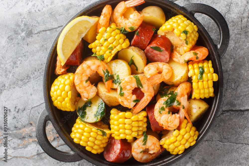 Shrimp boil heap with corn, baby potatoes, sausage and lemons closeup on the table. Horizontal top view from above