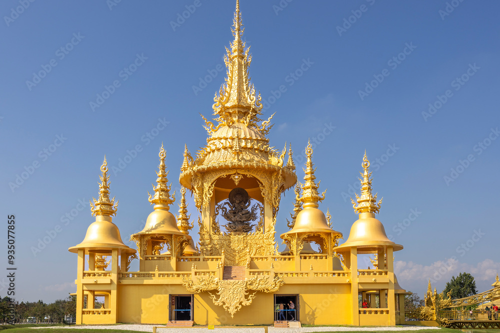 Naklejka premium The bright golden castle of Wat Rong Khun This temple stands out because of its pure white color. Contrasting with the glittering gold color of the intricately decorated patterns. It is a famous templ