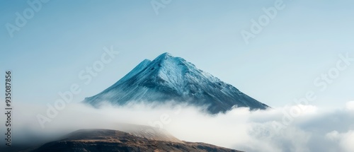  A towering mountain, its peak piercing the heart of a sky blanketed by clouds photo