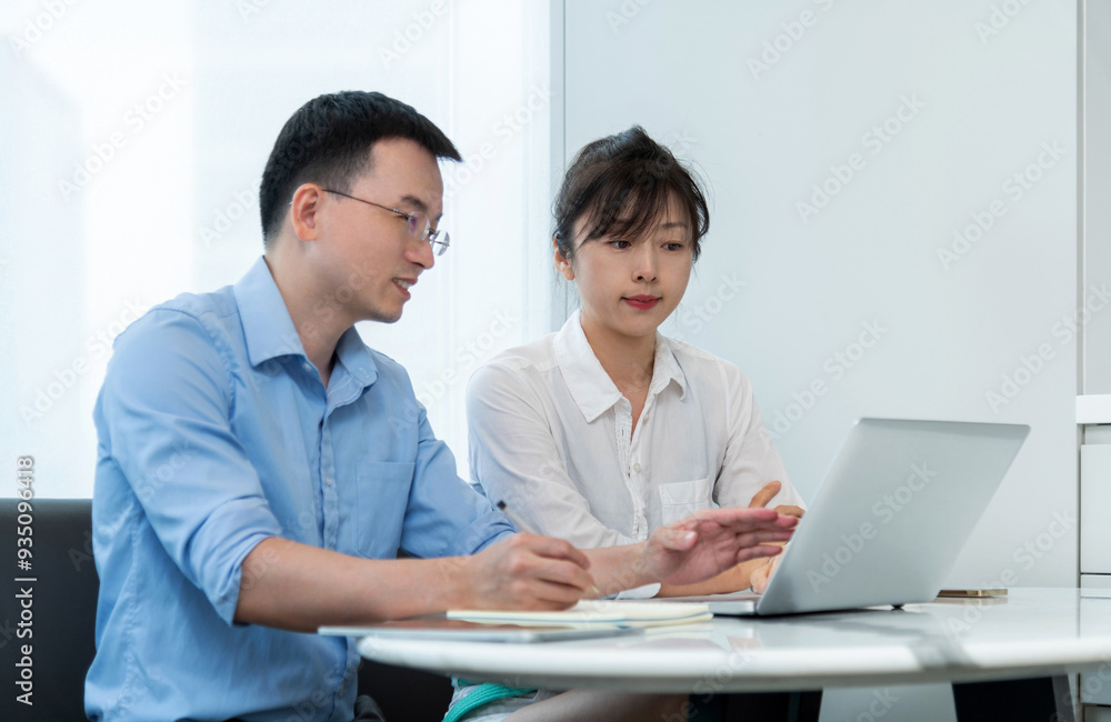 Two asian businesspeople working together in the office while using laptop Two asian businesspeople working together in the office while using laptop