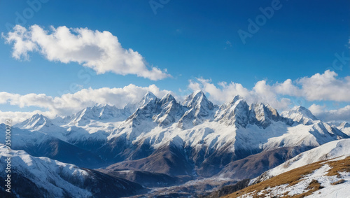 Panoramic view of a stunning snow-covered mountain range, with a clear blue sky and scattered clouds above.