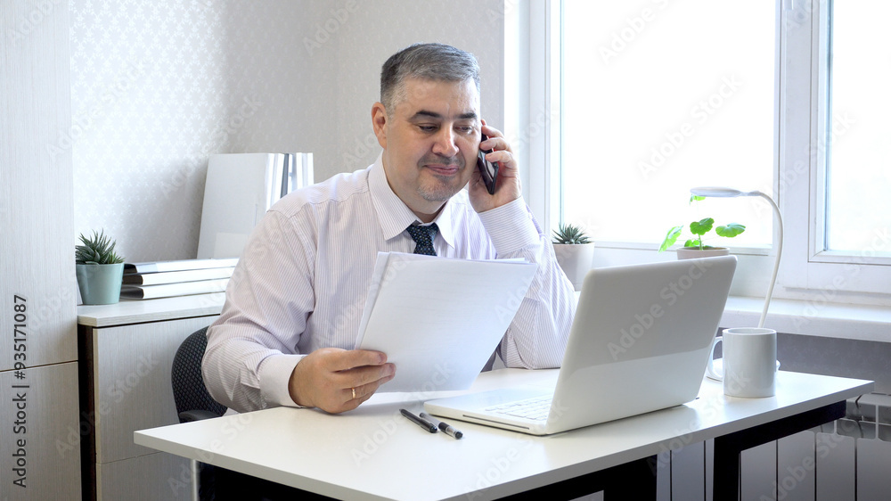 Man Working with Documents and Talking on Phone in Office Man Working with Documents and Talking on Phone in Office