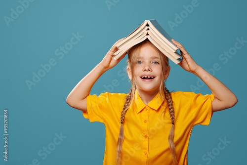 Back to school, cute girl with pile of books, smart child, read, knowledge. Blue background photo