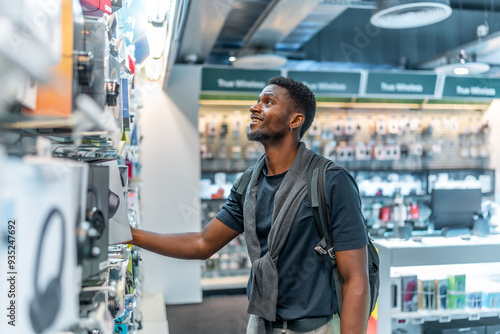 Foto Young african man in a tech store looking at headphones