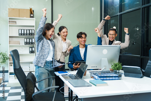 In an office, an Asian team meets at a desk, analyzing financial data on a monitor. They discuss business finance, operational guidelines, and strategies for success, data-driven decision-making. photo