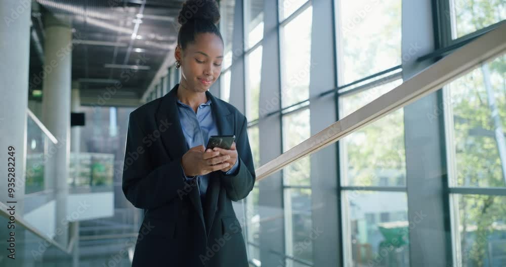 African Female Professional Walking Through a Modern Office Hall, Using Her Smartphone for Browsing Online. Young Woman Connected to the News, Social Network Data and Internet Applications African Female Professional Walking Through a Modern Office Hall, Using Her Smartphone for Browsing Online. Young Woman Connected to the News, Social Network Data and Internet Applications