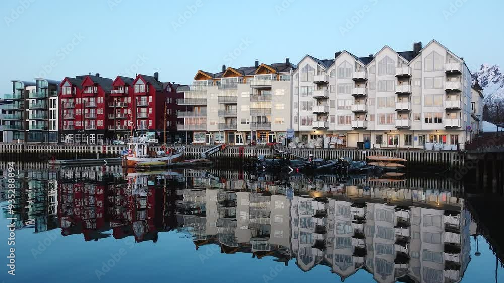 Discover the lively atmosphere of a picturesque coastal town nestled by a serene harbor. The scene features a row of modern buildings with vibrant facades alongside traditional fishing boats gently Discover the lively atmosphere of a picturesque coastal town nestled by a serene harbor. The scene features a row of modern buildings with vibrant facades alongside traditional fishing boats gently