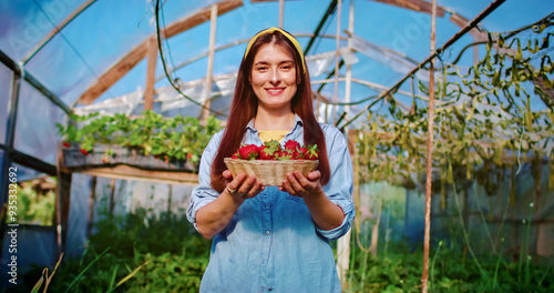 Принти на полотні Portrait of beautiful Caucasian female holding basket full of freshly picked strawberries smiles