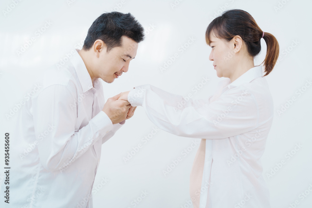 A happy Asian couple, expecting a baby, embraces in a cozy living room. The pregnant woman smiles warmly, while the man lovingly supports her, capturing a moment of joyful anticipation. A happy Asian couple, expecting a baby, embraces in a cozy living room. The pregnant woman smiles warmly, while the man lovingly supports her, capturing a moment of joyful anticipation.