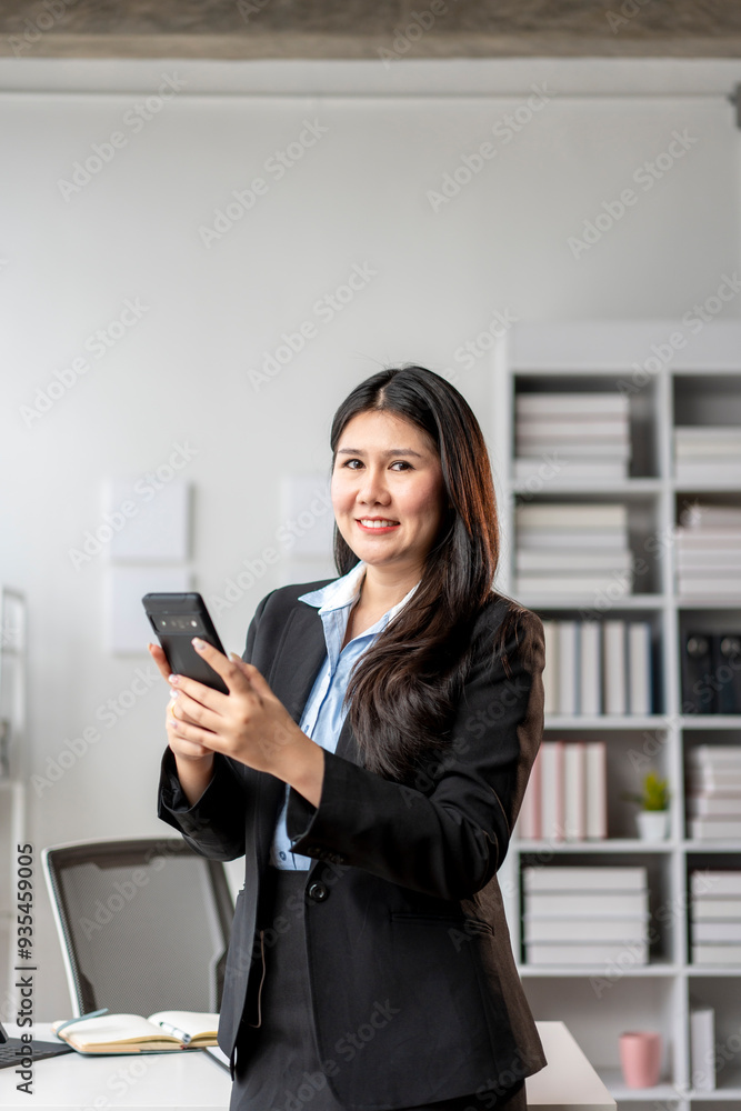 A woman in a business suit is smiling and holding a cell phone A woman in a business suit is smiling and holding a cell phone