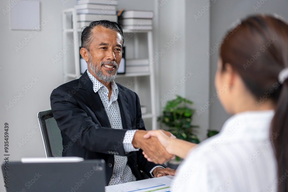 A man shakes hands with a woman in a business setting A man shakes hands with a woman in a business setting