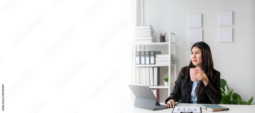 A woman in a business suit is sitting at a desk with a laptop A woman in a business suit is sitting at a desk with a laptop