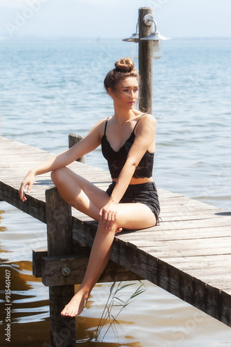 Entspannte Sommerstimmung am See: Frau im schwarzen Spitzen-Outfit auf einem Steg