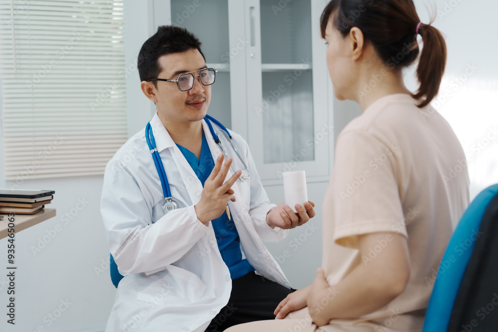 Fototapeta premium Asian female doctor listens to belly of pregnant mother during a prenatal exam in clinic. doctor provides caring advice, ensuring the health and happiness of the expecting mother and baby.