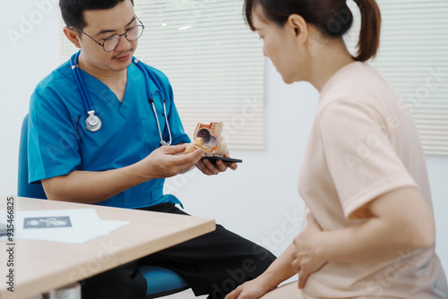 Asian female doctor listens to belly of pregnant mother during a prenatal exam in clinic. doctor provides caring advice, ensuring the health and happiness of the expecting mother and baby.