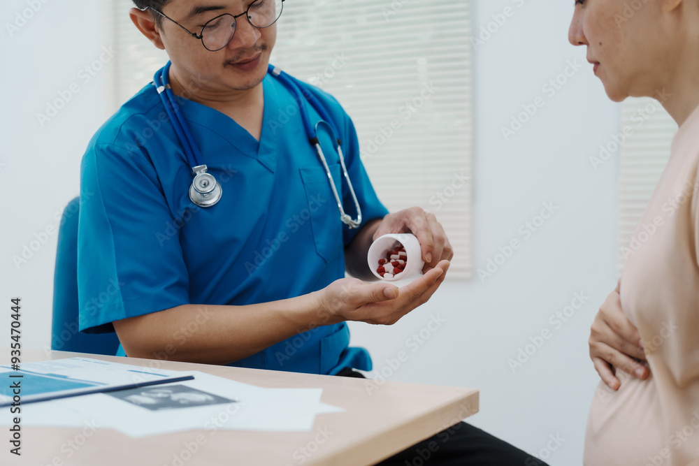 Fototapeta premium Asian female doctor listens to belly of pregnant mother during a prenatal exam in clinic. doctor provides caring advice, ensuring the health and happiness of the expecting mother and baby.